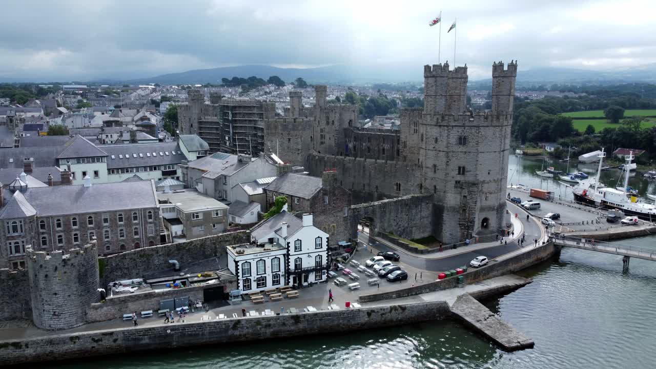 Veduta aerea dell'antico castello di Caernarfon, città portuale gallese, punto di riferimento medievale sul lungomare, con lento movimento a destra sopra il fiume