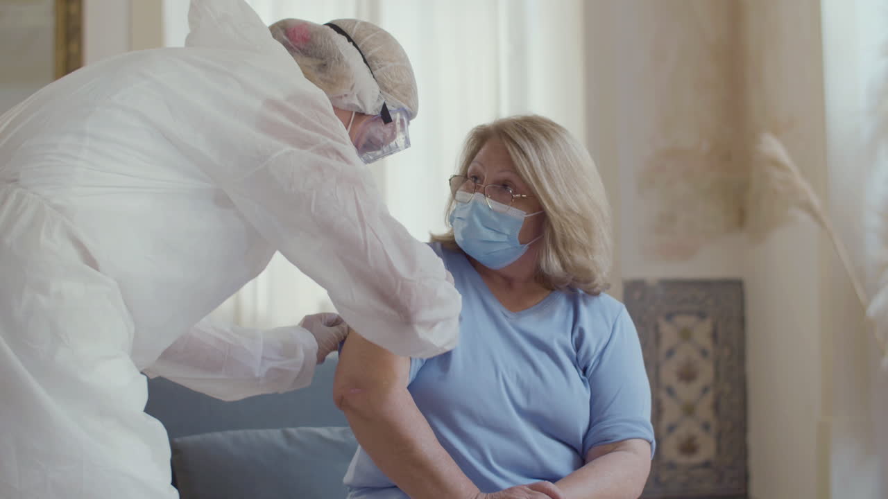 Infermiera che disinfetta il sito di iniezione sulla mano di una donna a casa.
