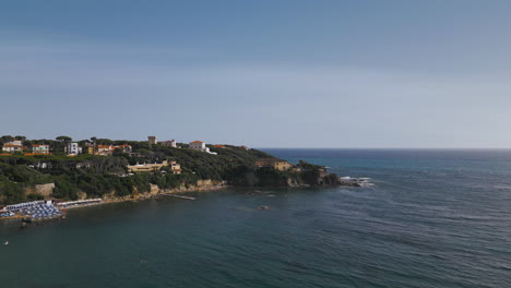 drone pullback from italian tuscan beach coastline, blue sky day