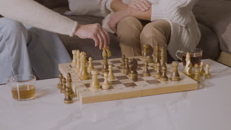 Two-Senior-Women-Playing-Chess-Sitting-On-Sofa-At-Home-2