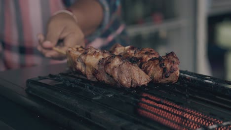 el chef gira la carne frita en la barbacoa eléctrica en el café de la calle