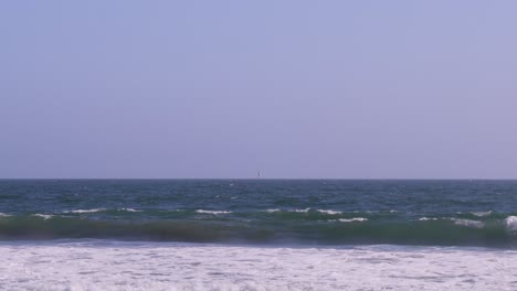 Panning-shot-of-a-lone-sailboat-in-the-ocean-on-a-bright-sunny-day-panning-from-left-to-right