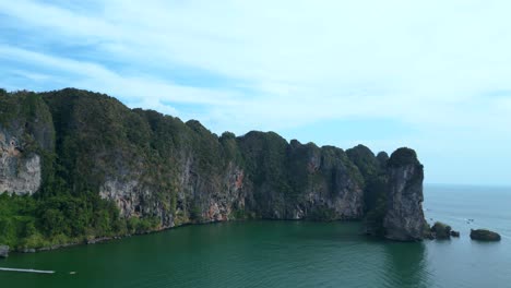 una vista impresionante de una bahía aislada con aguas turquesas, rodeada de altos acantilados cubiertos de exuberante vegetación verde
