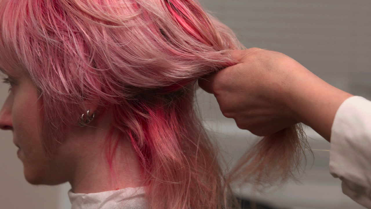 Peluquero cortando y peinando cabello rosa