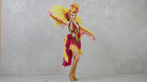 mujer hermosa joven en vestido de plumas rojas y amarillas bailando samba