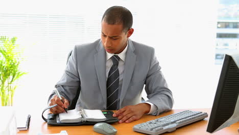 hombre de negocios trabajando en su escritorio y escribiendo en su diario