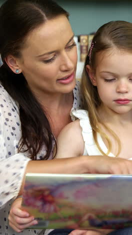 a mother is reading a book to her daughter