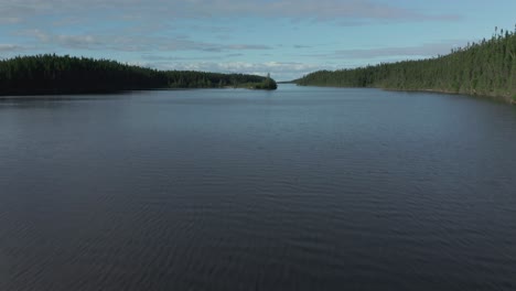 Drone-following-the-creek's-water-level-before-going-up-in-the-sky-and-showing-the-wide-creek-of-a-large-wild-lake-in-northern-Quebec