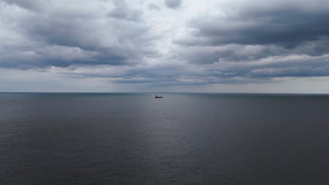 a solitary ship sails the calm ocean under a vast sky with a horizon blurred by grey clouds