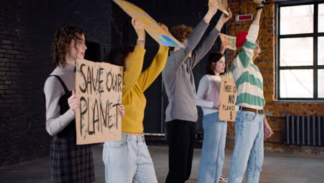 Side-view-of-young-environmental-activists-with-placards-and-megaphone-protesting-against-climate-change-inaction