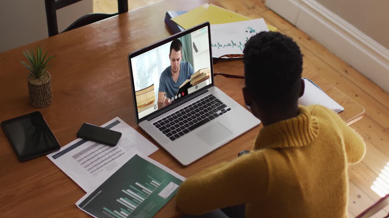 maestra afroamericana usando una computadora portátil en una videollamada con un estudiante varón
