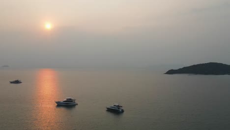 Aerial-View-Of-Yachts-Moored-In-Waters-Off-Ao-Suan-Yai-Beach-With-Golden-Orange-Sunset-Above-Horizon