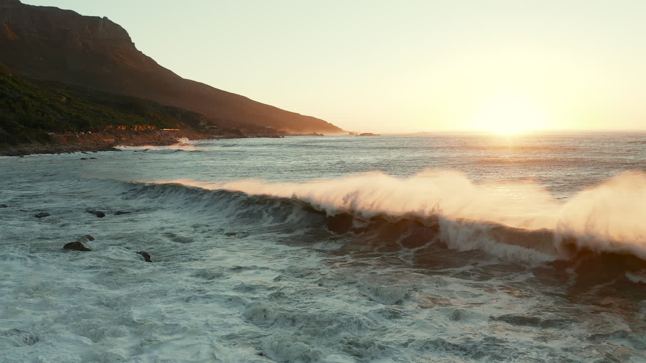 olas del mar rompiendo en la costa rocosa de la playa al atardecer en cape tow, sudáfrica