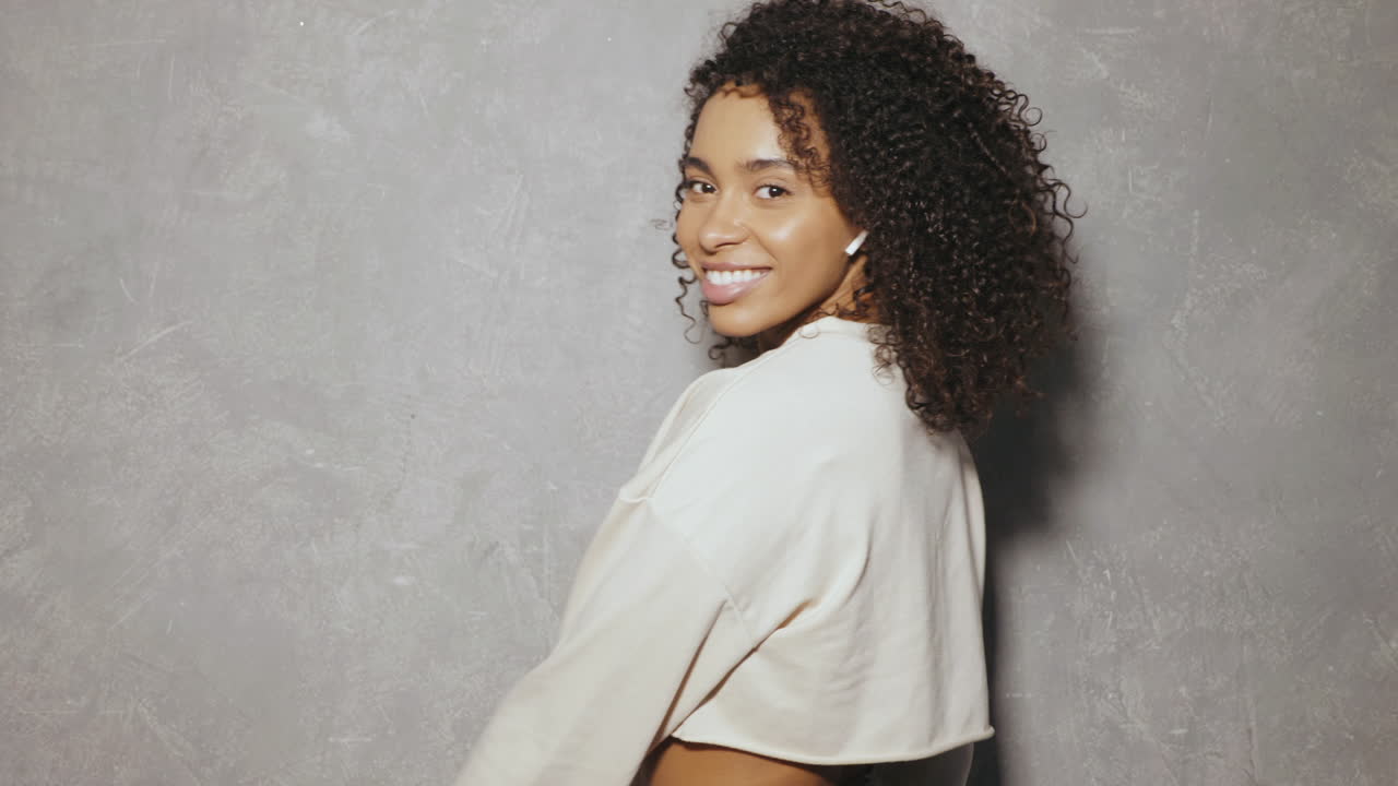 женщина с кудрявыми волосами и беспроводными наушниками