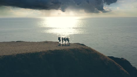 the four tourists standing on the mountain top near the sea