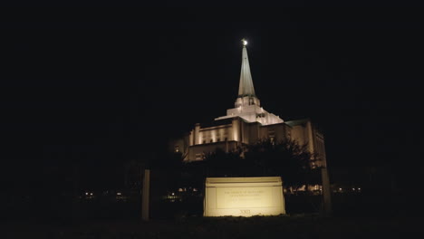 templo mormón lds en gilbert, arizona con letrero de edificio de la iglesia en la noche | la luna retroiluminó el ángulo moroni en la parte superior de la aguja