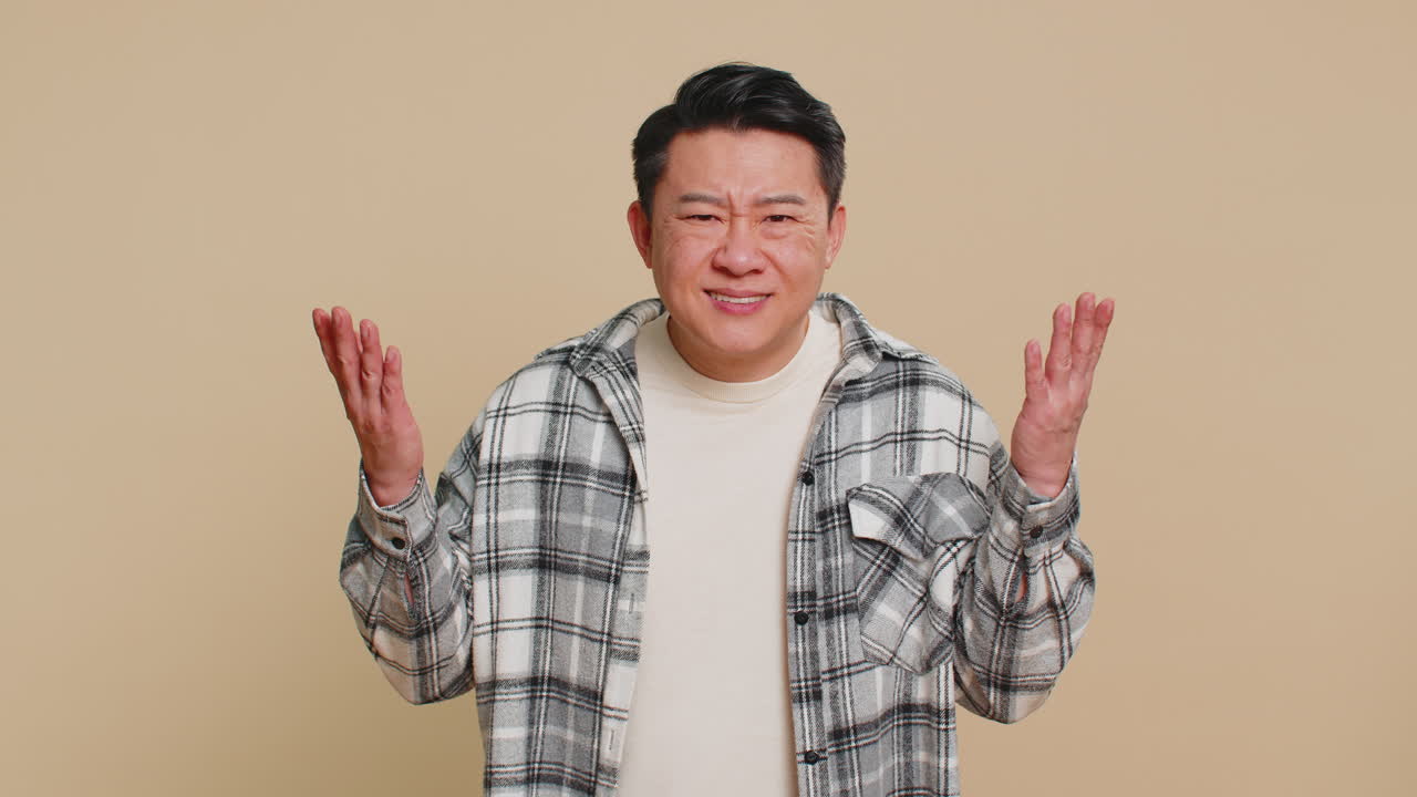 Asian man trying hear you looking confused and frowning keeping arm near ear for louder voice