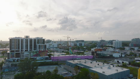 Tight-flight-around-tower-crane-and-revealing-view-of-buildings-in-urban-neighbourhood-at-twilight.-Miami,-USA