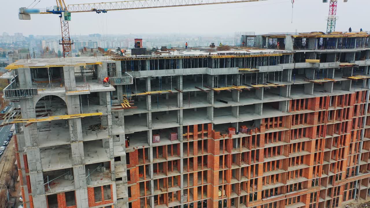 Massive residential building at construction site. Drone aerial view of new development with cityscape. Wide view of a new building with urban city behind.