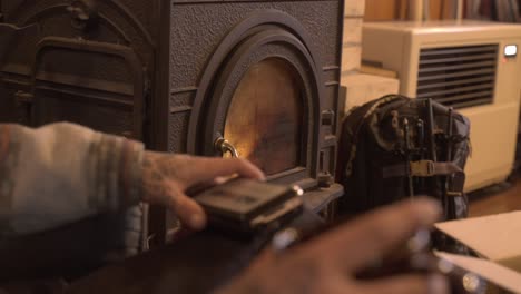 cozy indoor scene with hands tending a wood stove in a warm, rustic setting in iwanai, hokkaido