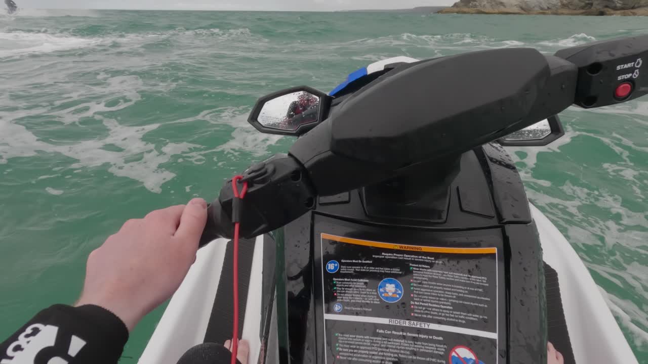 Rekaman POV seorang pengendara jet ski duduk di atas jet ski saat ombak bergelombang di lepas pantai Newquay.