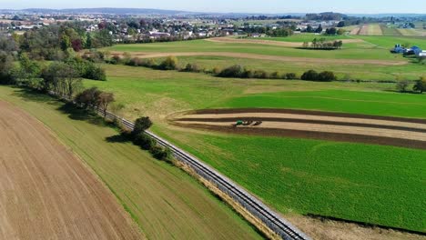 amish farm workers organically fertilizing there fields as seen by a drone
