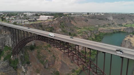 Slow-motion-aerial-view-of-vehicles-driving-across-the-Perrine-Memorial-Bridge-high-above-the-Snake-River-Canyon-in-Twin-Falls,-Idaho-during-the-summer