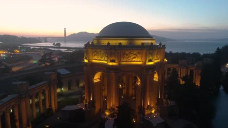 Aerial-view-of-Palace-of-Fine-Arts-at-dusk-with-the-golden-gate-bridge-in-the-background-in-San-Francisco