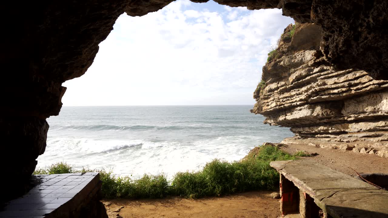 Cucabrera Cave frames the Cantabrian Sea with waves crashing against a rocky coastal cliff