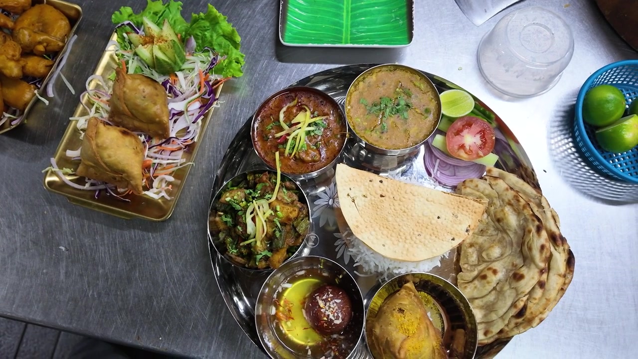 Kamera dari Atas Menyapu Samosa, Pakora, dan Piring Thali di Permukaan Baja Tahan Karat