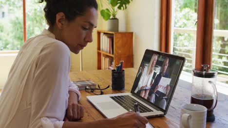 Afroamerikanische-Frau-Macht-Sich-Notizen,-Während-Sie-Zu-Hause-Einen-Videoanruf-Auf-Dem-Laptop-Führt