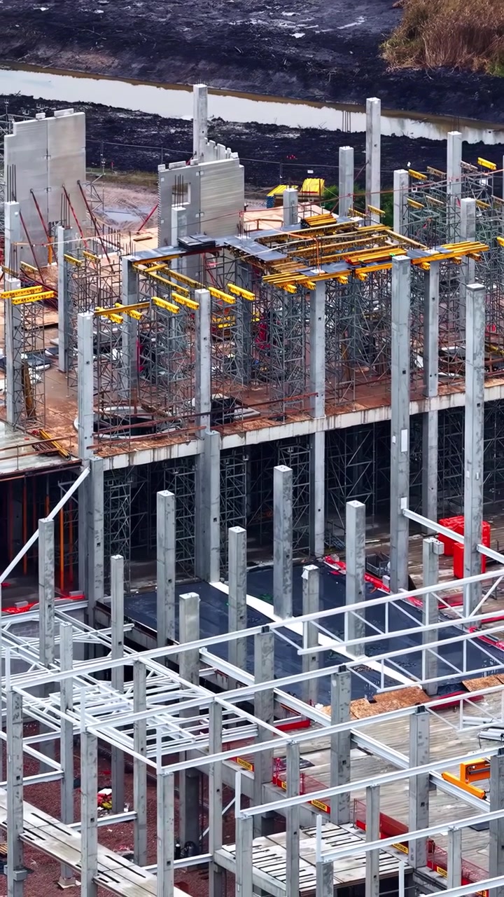 Steel framework and scaffolding rise at a large construction site near wetlands