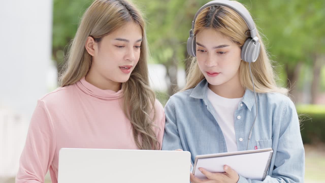 Two Asian girls student partners are working on a laptop help study together