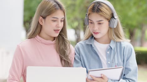 two asian girls student partners are working on a laptop help study together