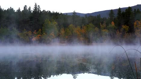 early morning mist over lake against a background of fall foliage