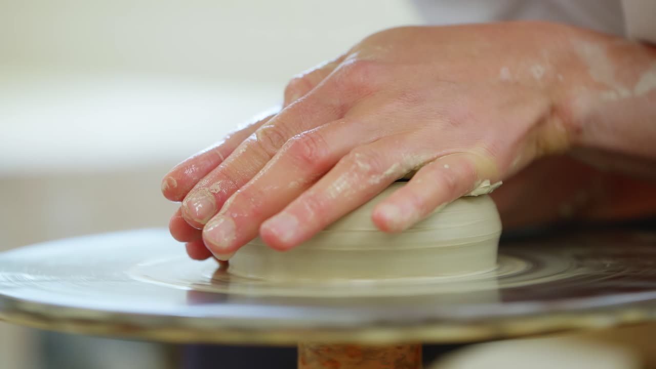 Hands shaping clay on a spinning potter's wheel