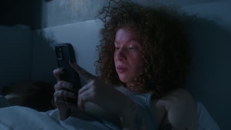 mujer usando teléfono inteligente en la cama por la noche