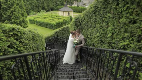 Newlyweds.-Caucasian-groom-with-bride-stay-on-stairs-in-park.-Wedding-couple.-Man-and-woman-in-love