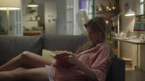 woman reading book in evening at home