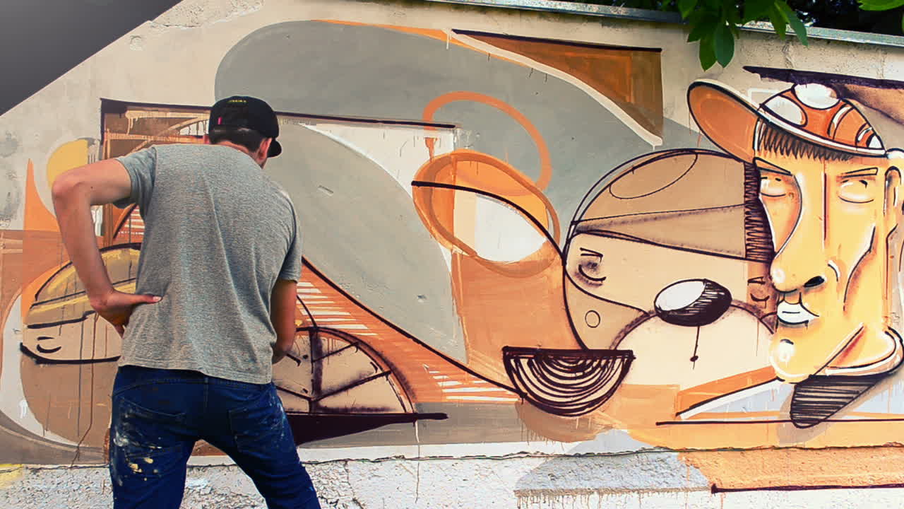 Kunstneren tegner graffiti på et gjerde. Graffiti på et gjerde