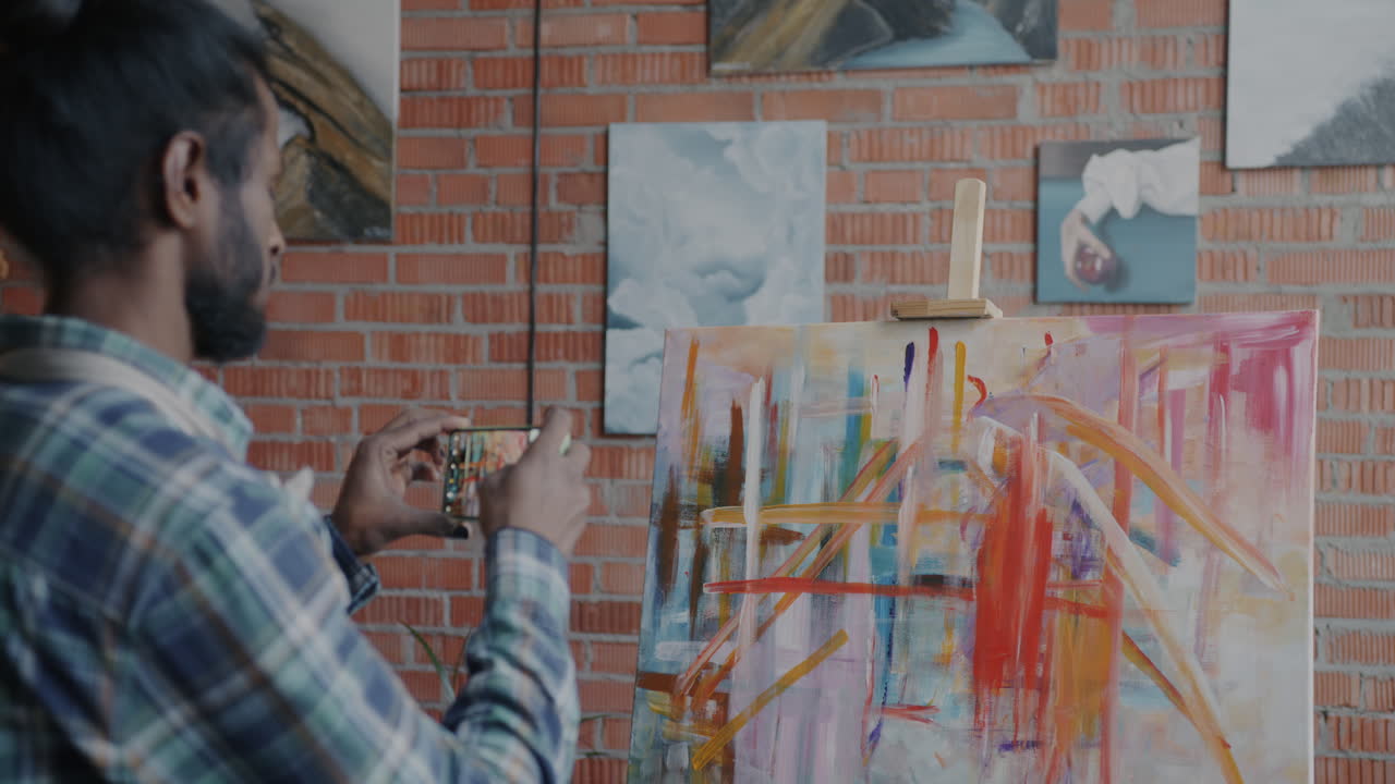 Artist taking a picture of an abstract painting in a studio