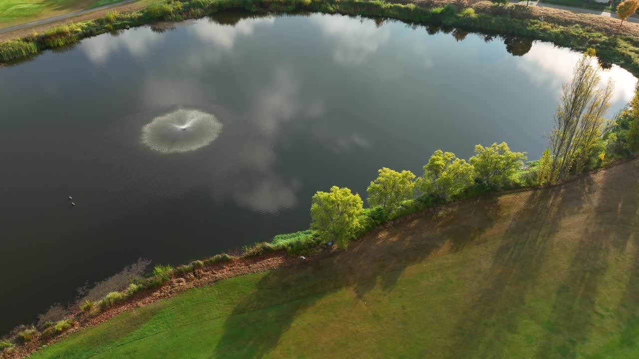 Aerial view of a public pond with a fountain during a warm sunset