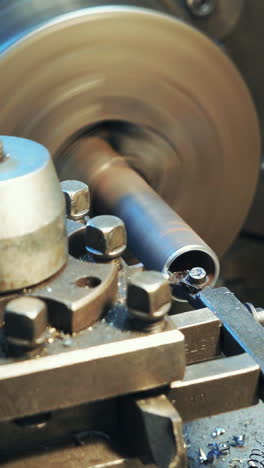 a lathe processes metal blank in the factory. shavings fall to the floor in the room.close-up. vertical video