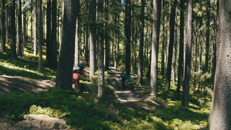 A-group-of-three-men-riding-mountain-bikes-fast-down-the-trail---cinematic-moving-camera-shot