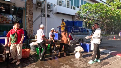 people measuring fish at a market stall