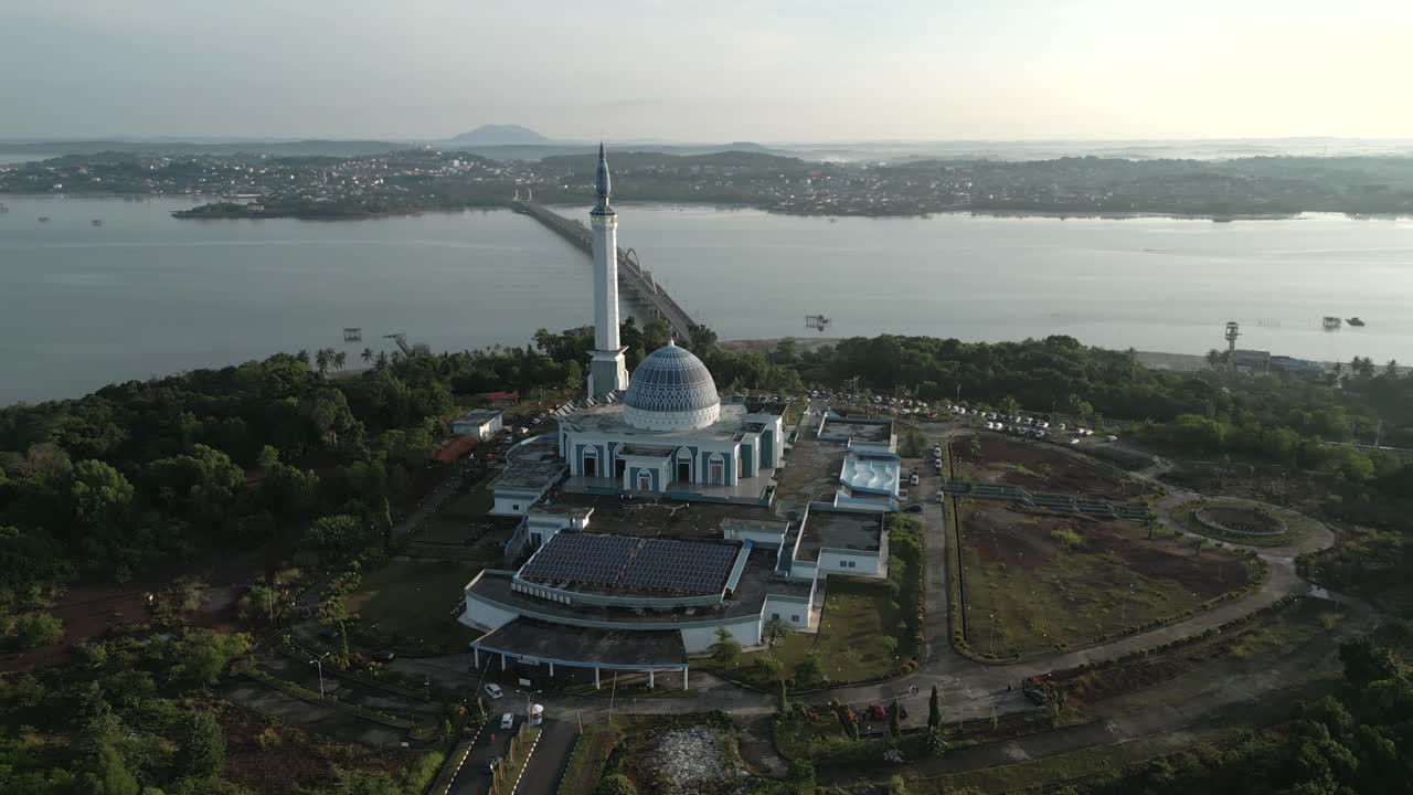 Full aerial view of the Provincial Mosque (Masjid Raya Nur Ilahi) and Dompak Bridge, with Bintan Island in the distance. Filmed on Dompak Island, Indonesia - Pulau Dompak, Indonesia