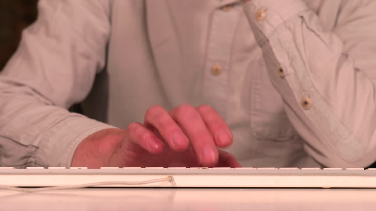 расстроенный человек стучит пальцами и печатает на белой клавиатуре