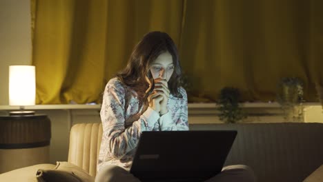 una joven mujer viendo una película de terror en su portátil por la noche. la joven está asustada y tensa.