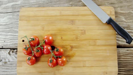 tomates de cereza y cuchillo de cocina en la tabla de cortar