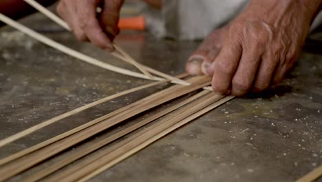 viejas manos de cerca de artesanos haciendo cestas con bambú en un entorno rural